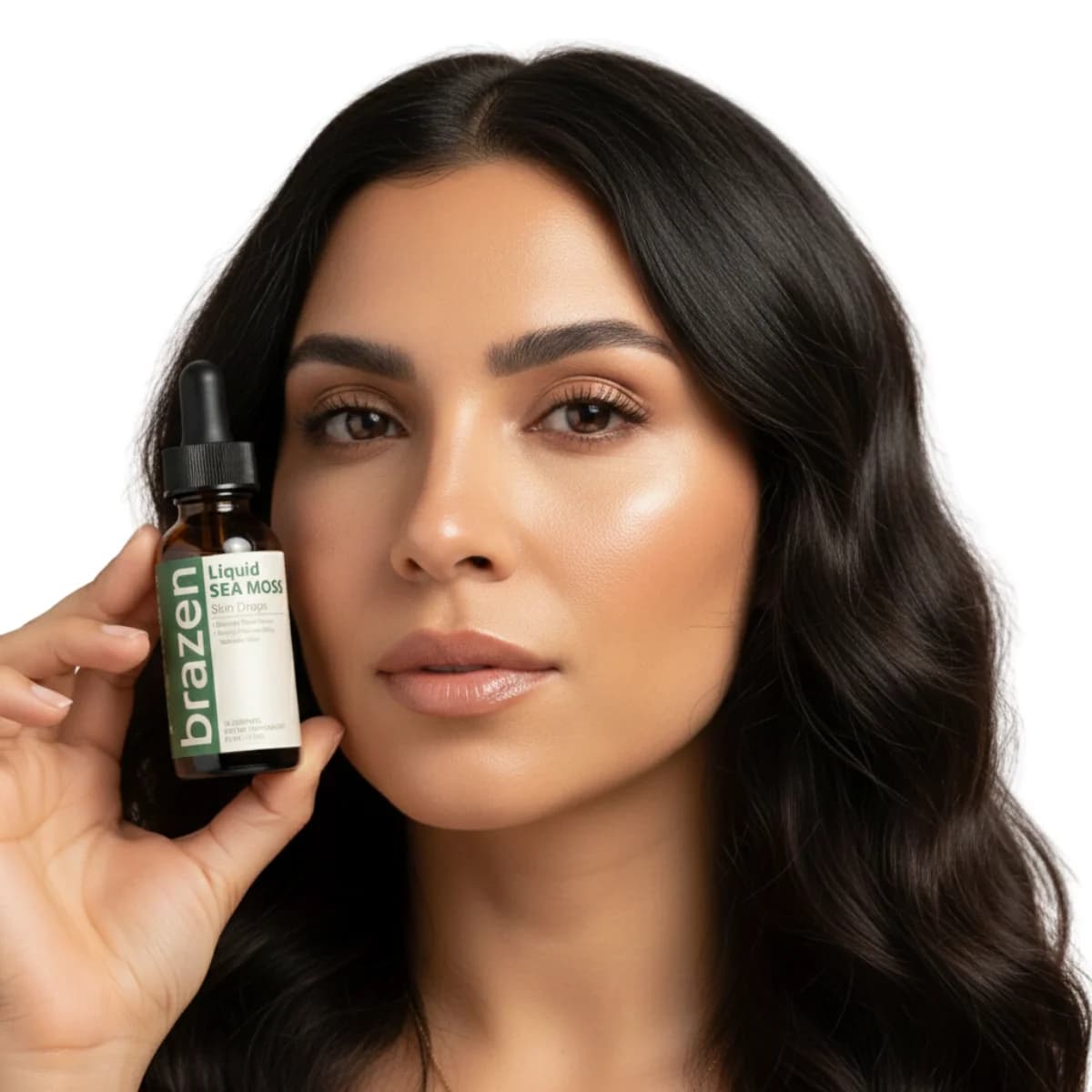 Woman with long dark hair holding a bottle of Brazen Liquid Sea Moss Skin Drops beside her cheek